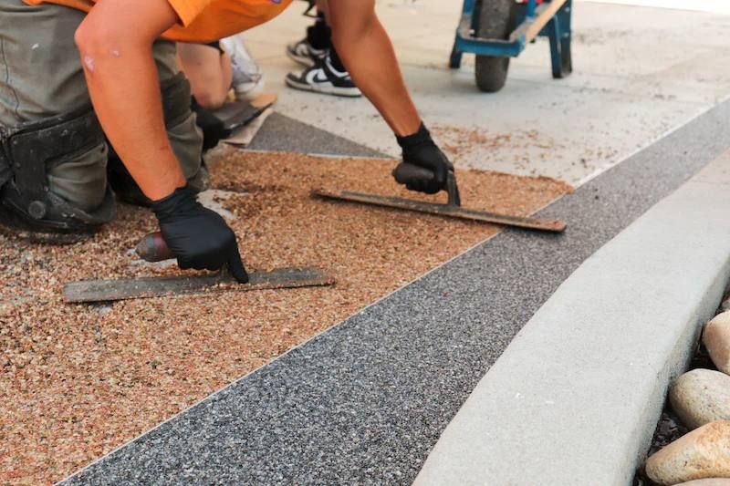 Worker troweling a resin-bound stone border